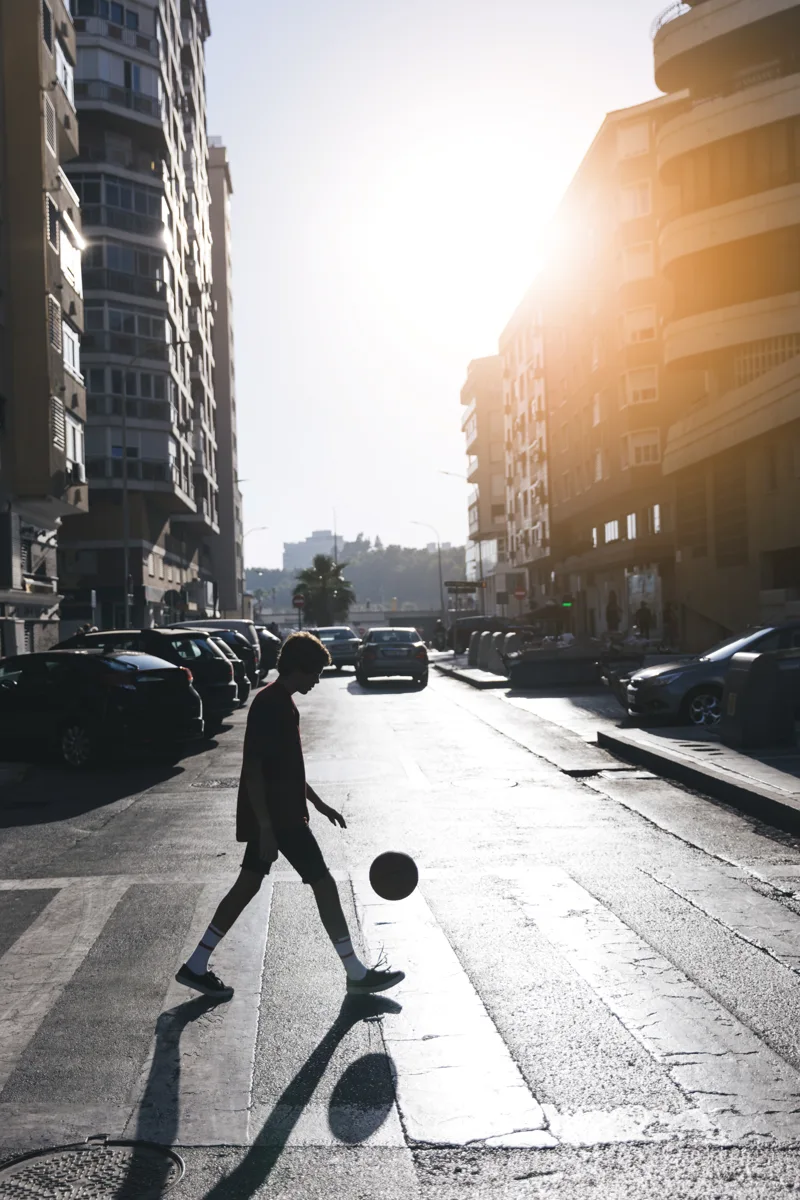 A basketball player silhouetted against sunlight on a New York street